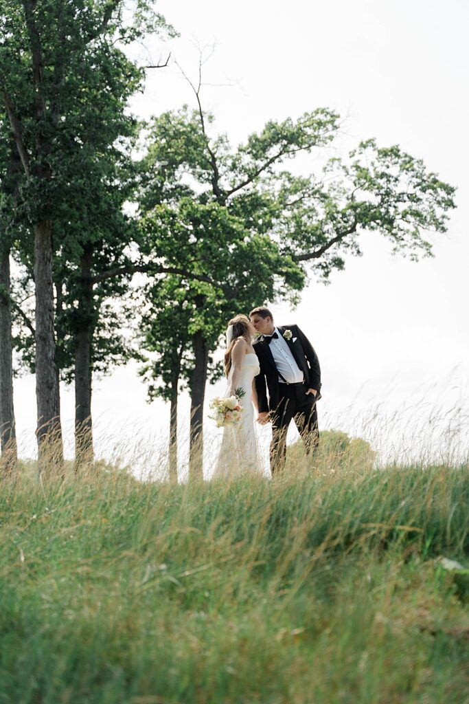 bride and groom kiss in field