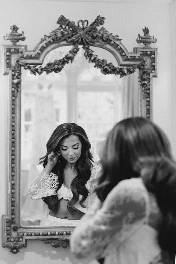 bride puts earrings on in mirror