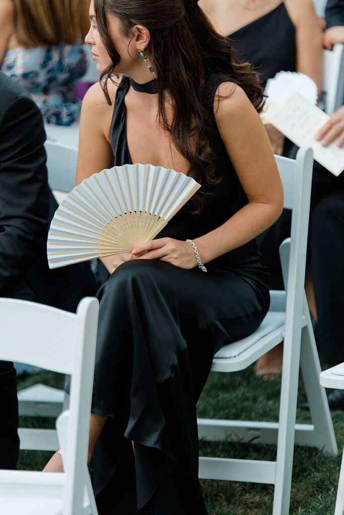 guest in black dress with ceremony fan